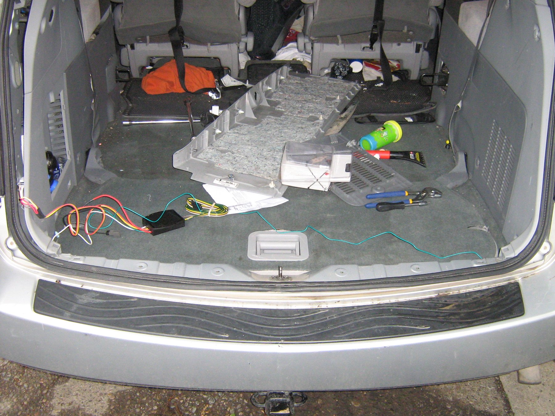 pose d'un faisceau électrique d'attelage dans le coffre d'une voiture, fils et boîtier de connexion au sol avec les outils
