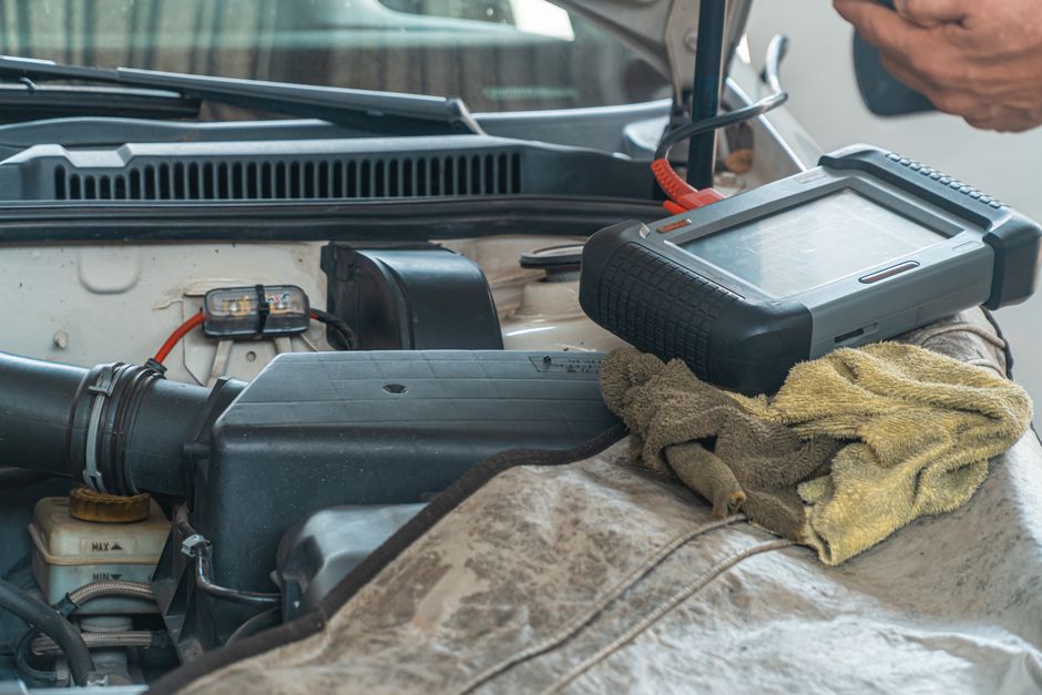 Close-up of a car engine inspection using a diagnostic tool in a garage setting, showcasing automotive maintenance and r