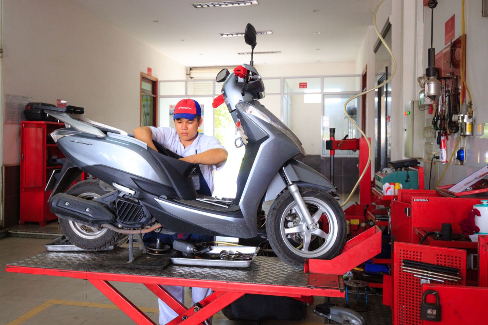 Mécanicien vérifiant la chaîne et le niveau d'huile d'une moto dans un garage