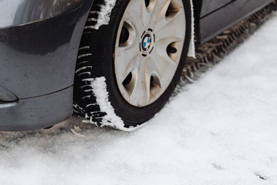 Close-up of a car’s tire on a snowy road, highlighting the winter season conditions.