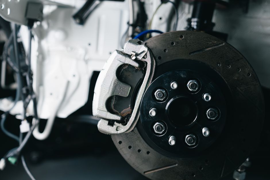 Detailed view of a car’s brake caliper and disc in a workshop setting.